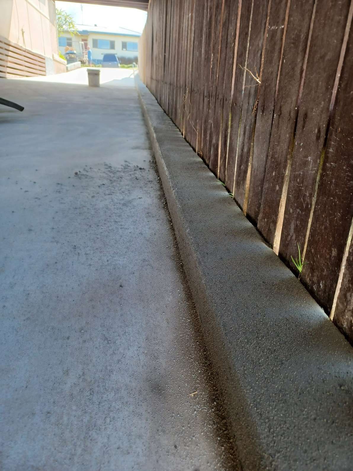 A Concrete Walkway With a Wooden Fence in the Background — Brocksolid Concrete in Pillar Valley, NSW