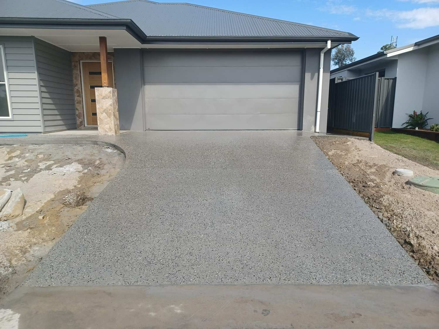 A Driveway Leading to a House With a Garage Door — Brocksolid Concrete in Pillar Valley, NSW