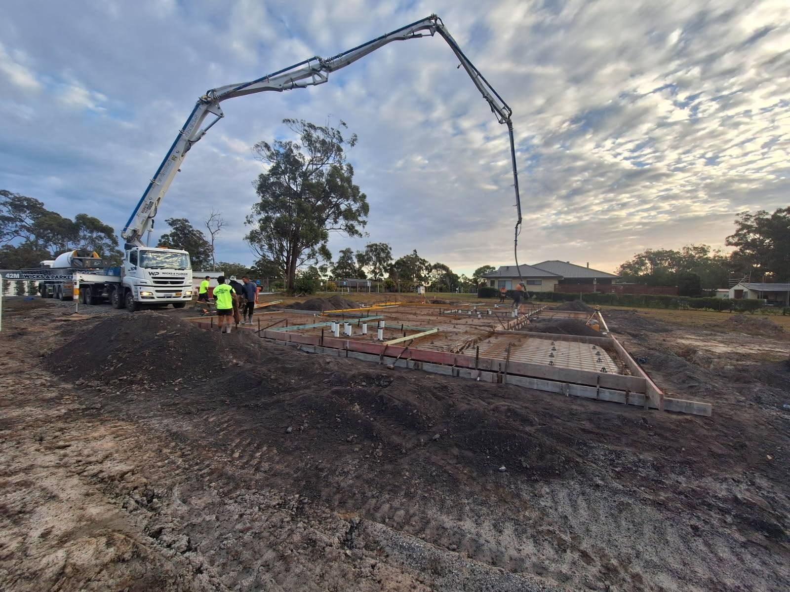 A Brick House With a Concrete Patio in Front of It — Brocksolid Concrete in Pillar Valley, NSW
