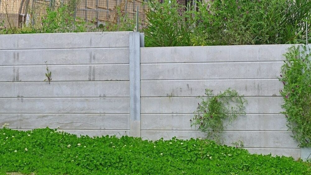 A Concrete Fence is Surrounded by Green Grass and Trees — Brocksolid Concrete in Pillar Valley, NSW