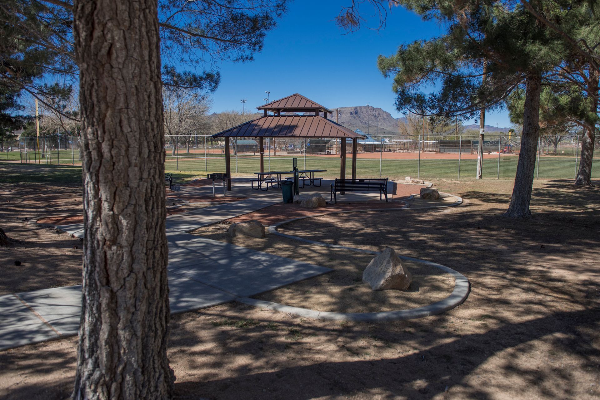 A picnic area in a park with a gazebo and picnic tables.
