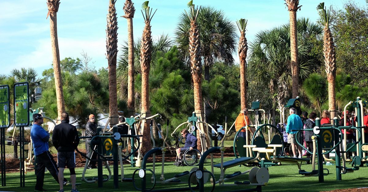 A group of people are standing around a gym in a park.