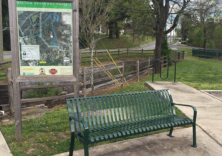 A green bench is sitting in front of a map of a park.