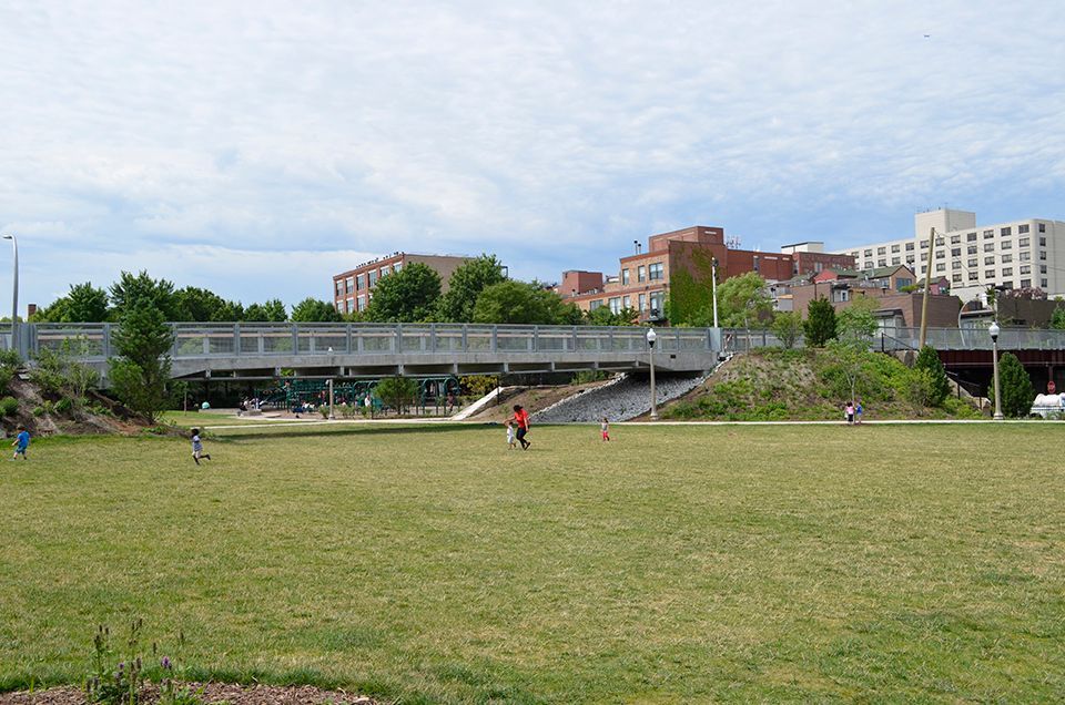 A large grassy field with a bridge in the background
