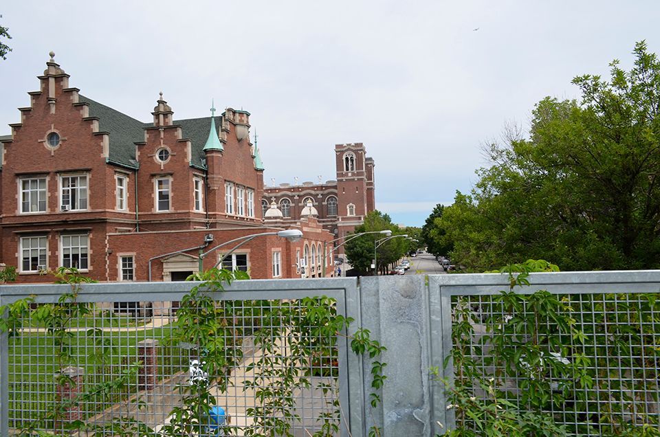 A large brick building is behind a metal fence
