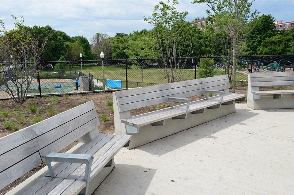 A row of wooden benches in a park with trees in the background