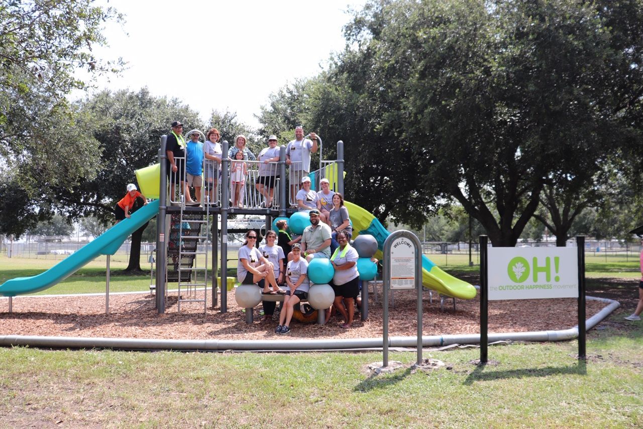 A group of people are posing for a picture in front of a playground.
