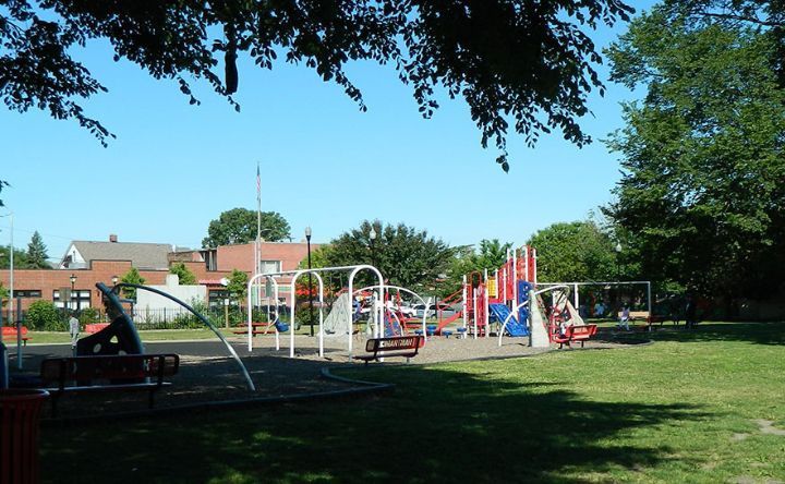 A playground is surrounded by trees and grass on a sunny day