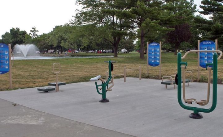 A park with exercise equipment and a fountain in the background