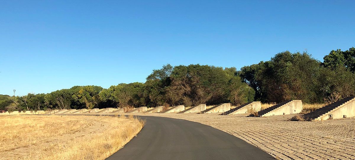 A road that is going through a field with trees on the side.