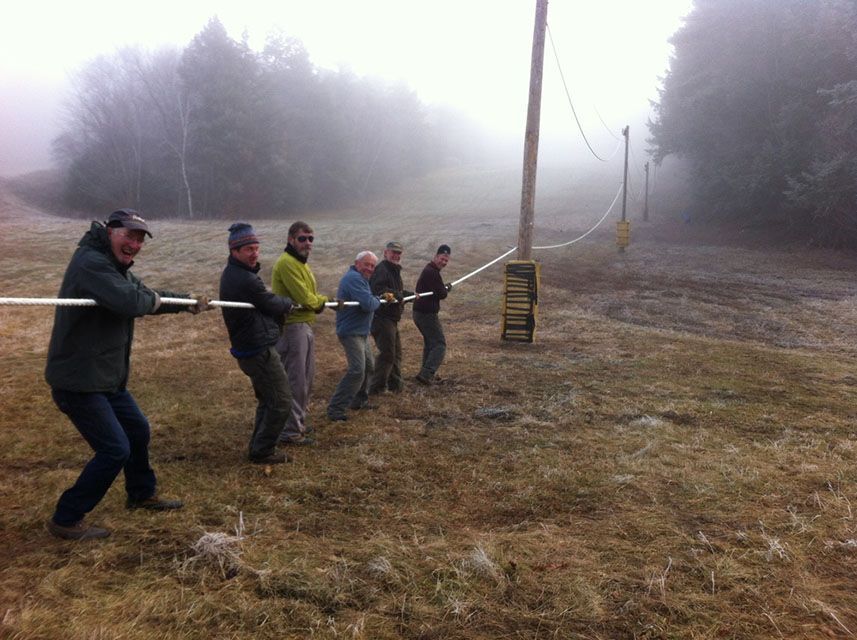A group of men are pulling a rope in a field.
