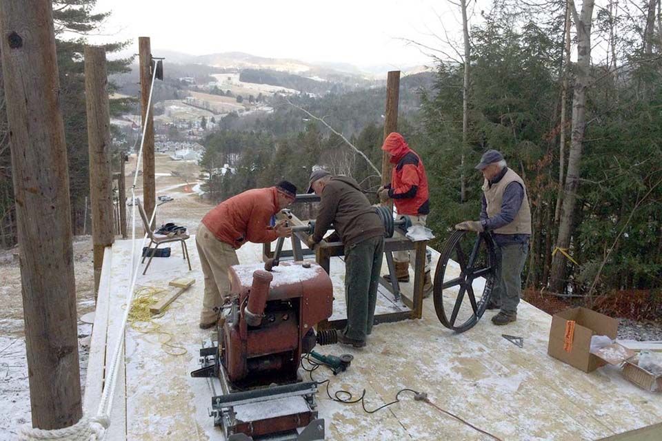 A group of men are working on a machine in the snow