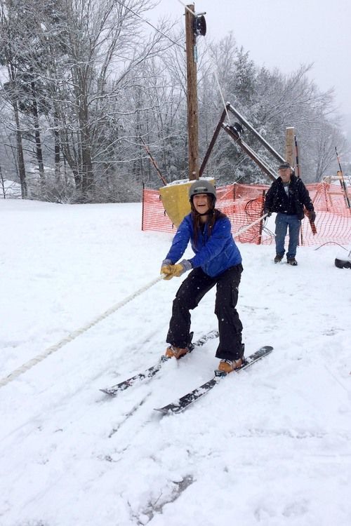 A woman is skiing down a snow covered slope