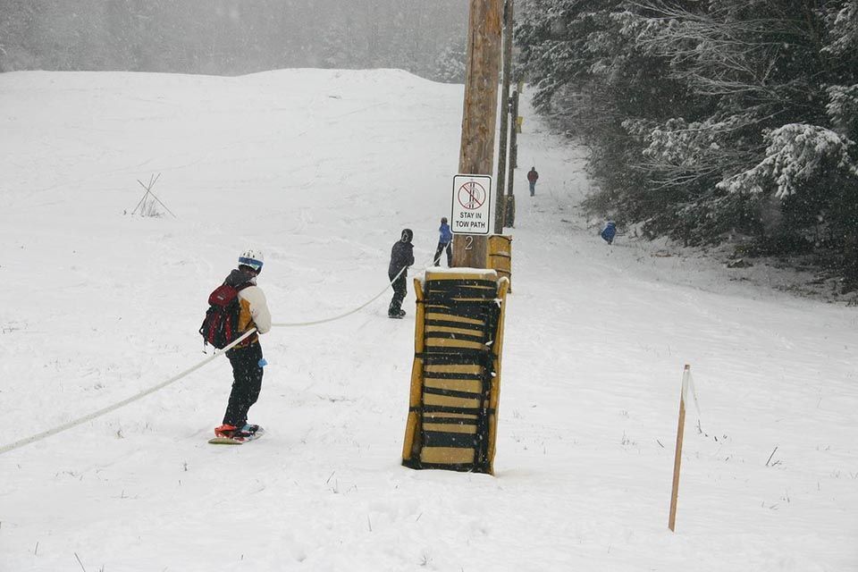 A person skiing down a snowy slope next to a sign that says no parking