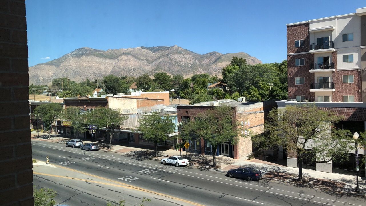 A view of a city street from a window with mountains in the background.