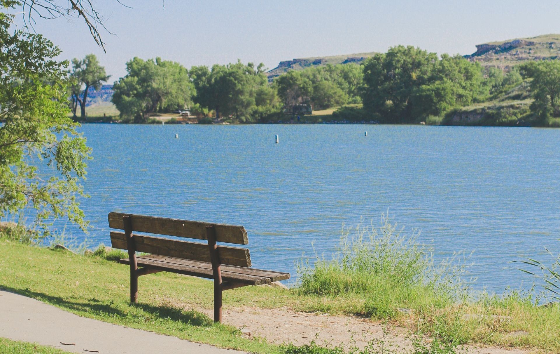 A wooden bench is sitting on the shore of a lake.