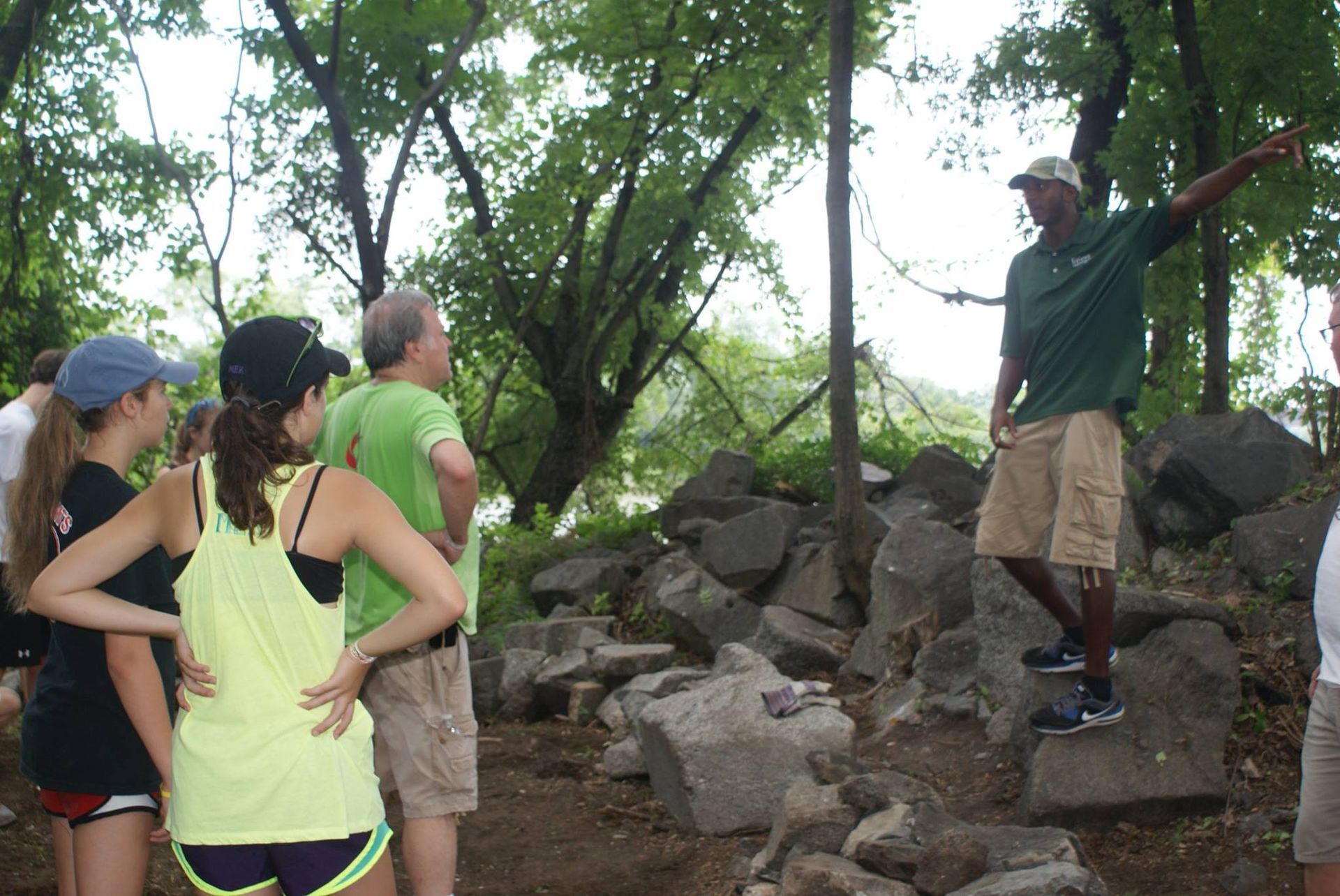 A man in a green shirt is talking to a group of people
