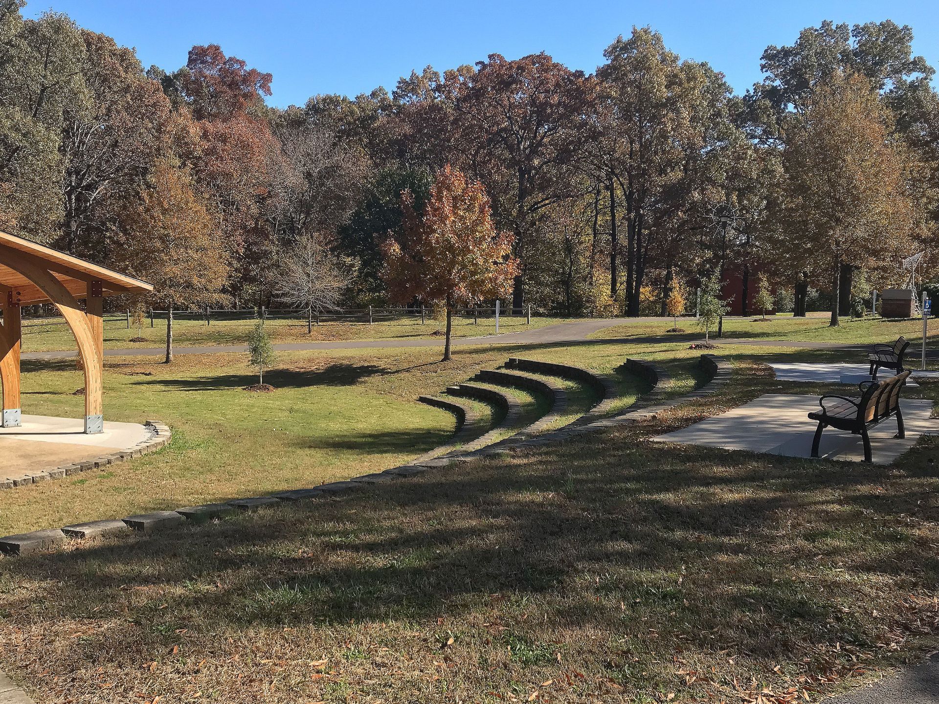 A park with a gazebo and benches and trees in the background