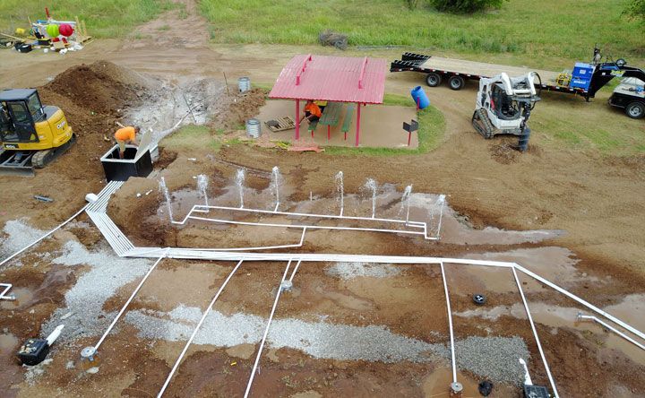 An aerial view of a fountain being built in a dirt field.