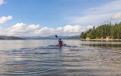 A person is paddling a kayak on a lake.