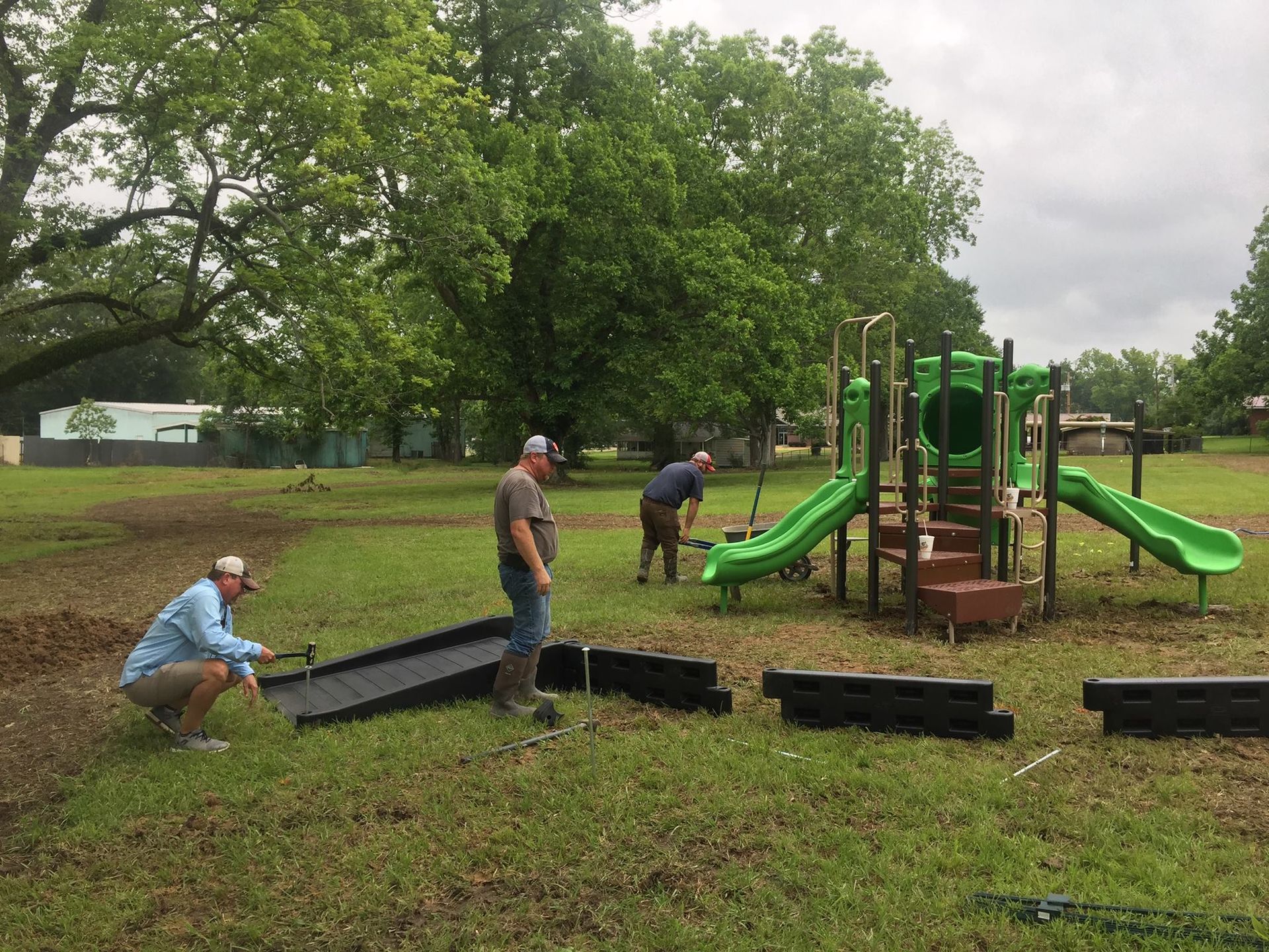 A group of men are working on a playground in a park.