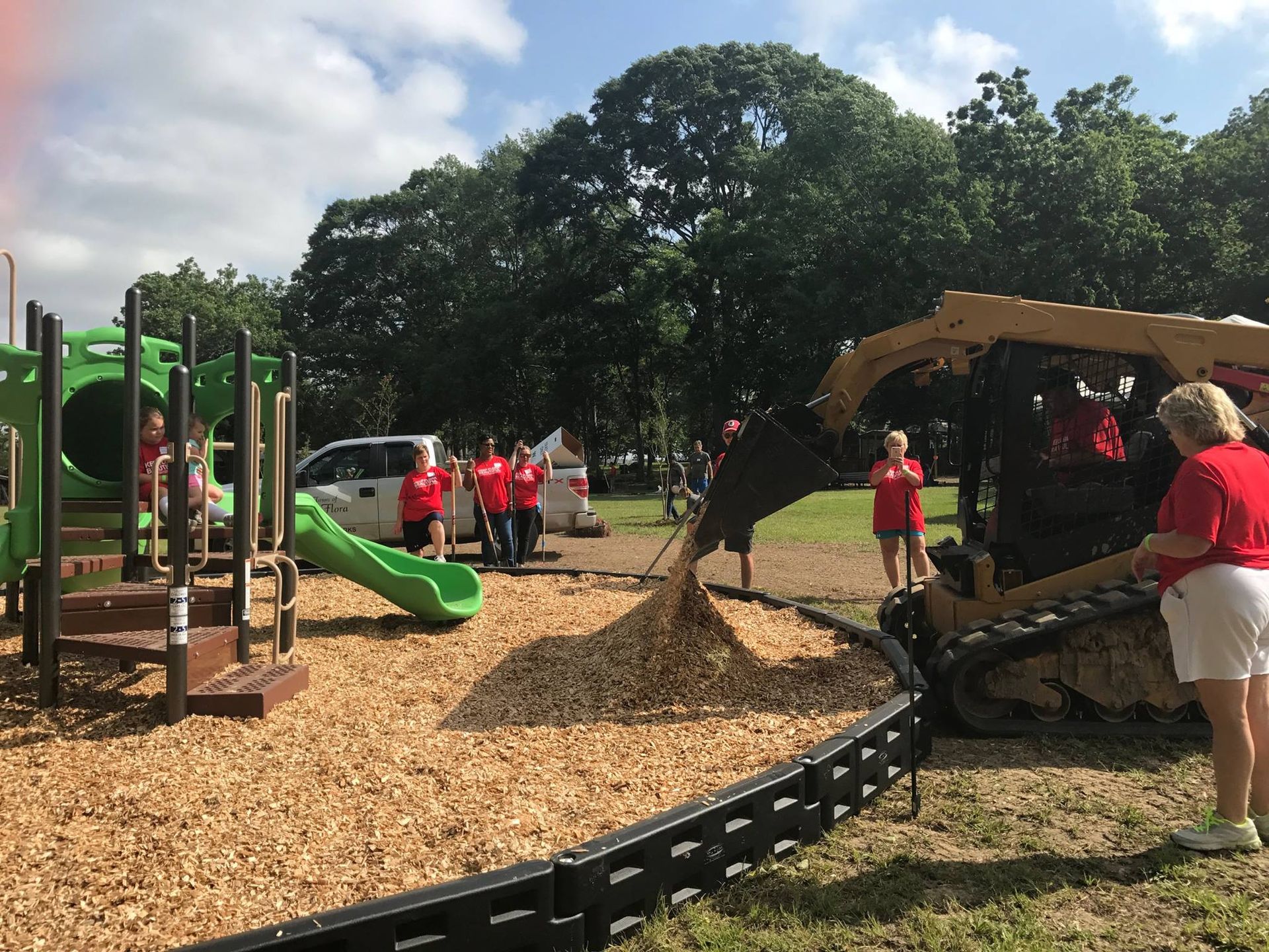 A group of people are working on a playground with a bulldozer.