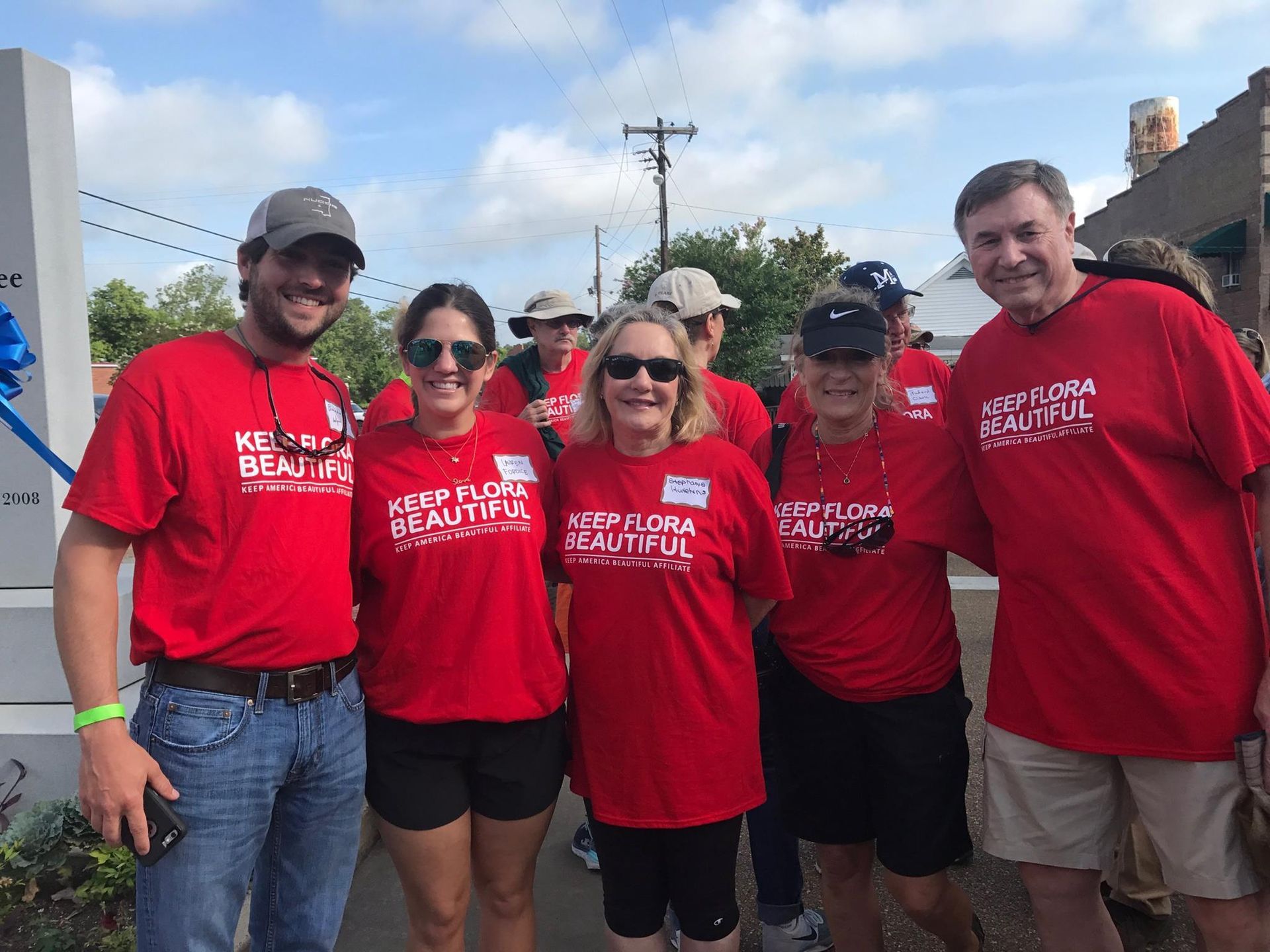 A group of people wearing red shirts that say keep florida beautiful are posing for a picture.
