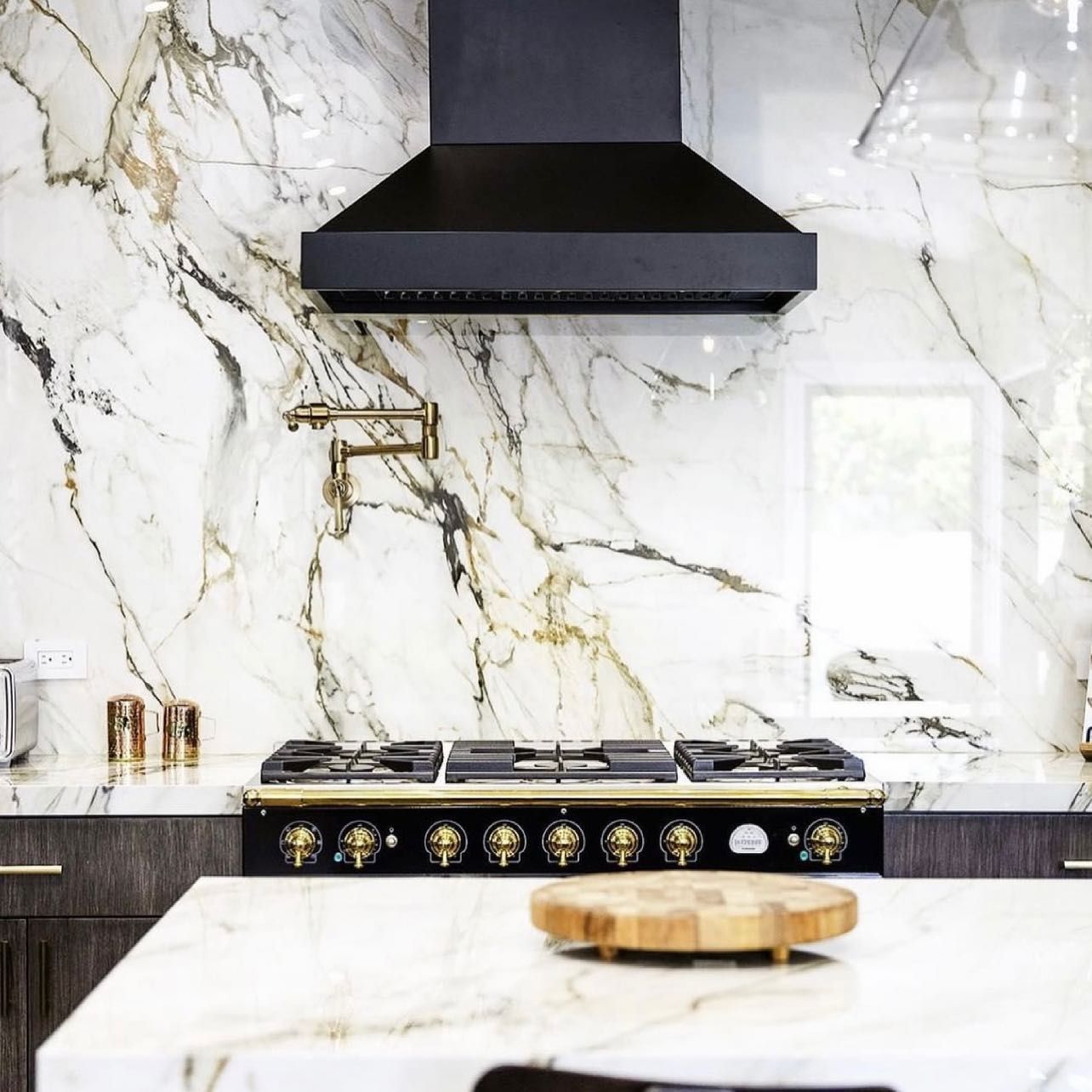 A kitchen with a stove top oven and a marble wall