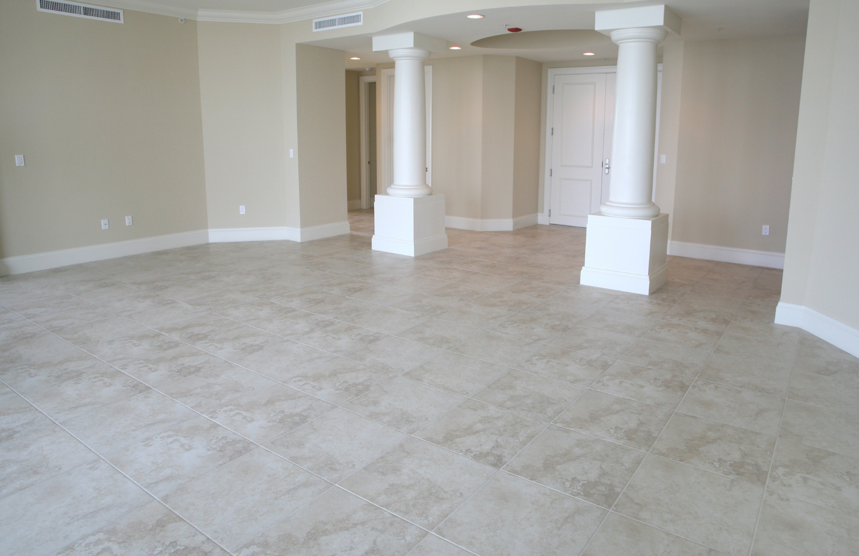 A large empty room with tile floors and white columns.