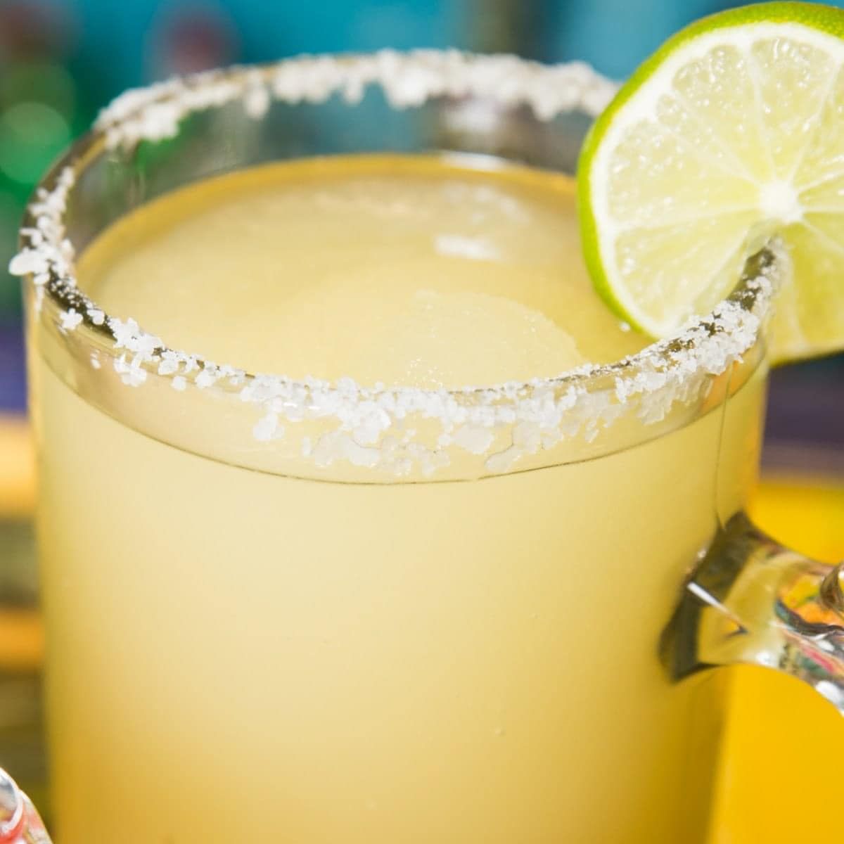 Frozen margarita in a glass with salt rim and lime wedge.