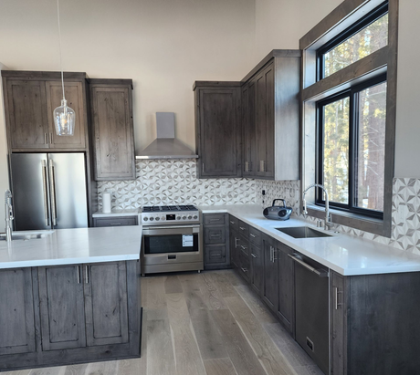 Modern kitchen with dark wood cabinets, white countertops, stainless appliances, and large windows