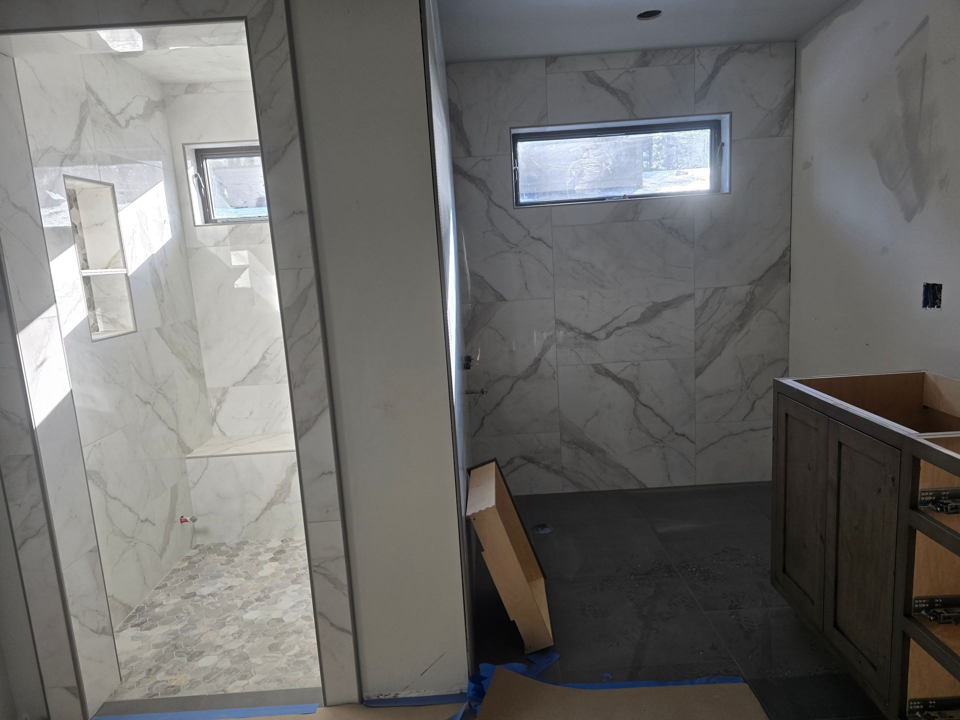 Small unfinished bathroom with tiled shower, narrow window, and vanity under construction