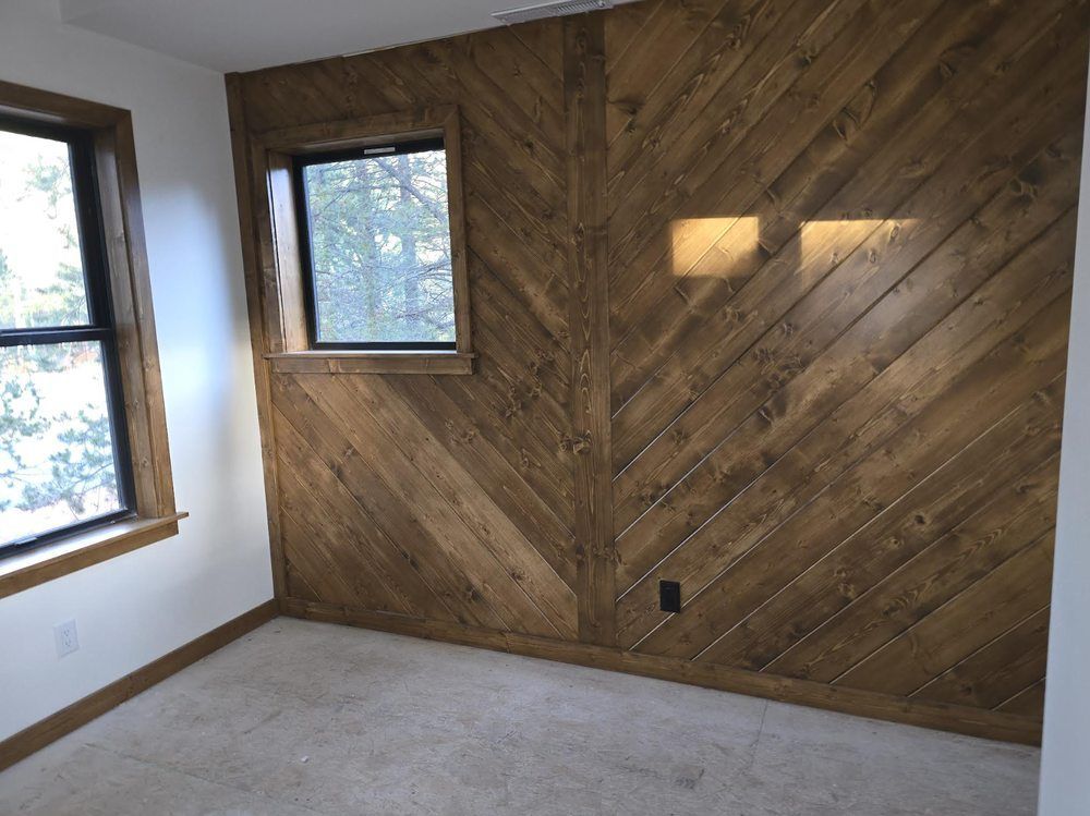 Empty room with wood accent wall, two windows, and beige carpet