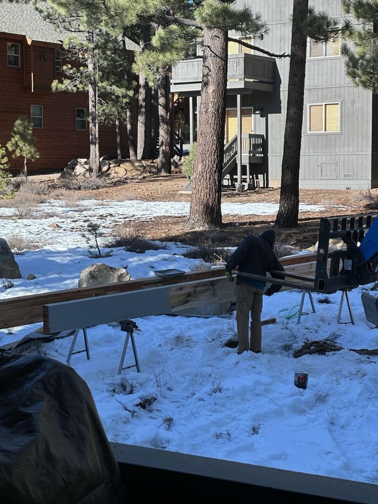 Snowy backyard with a wooden bench and trees in front of a house