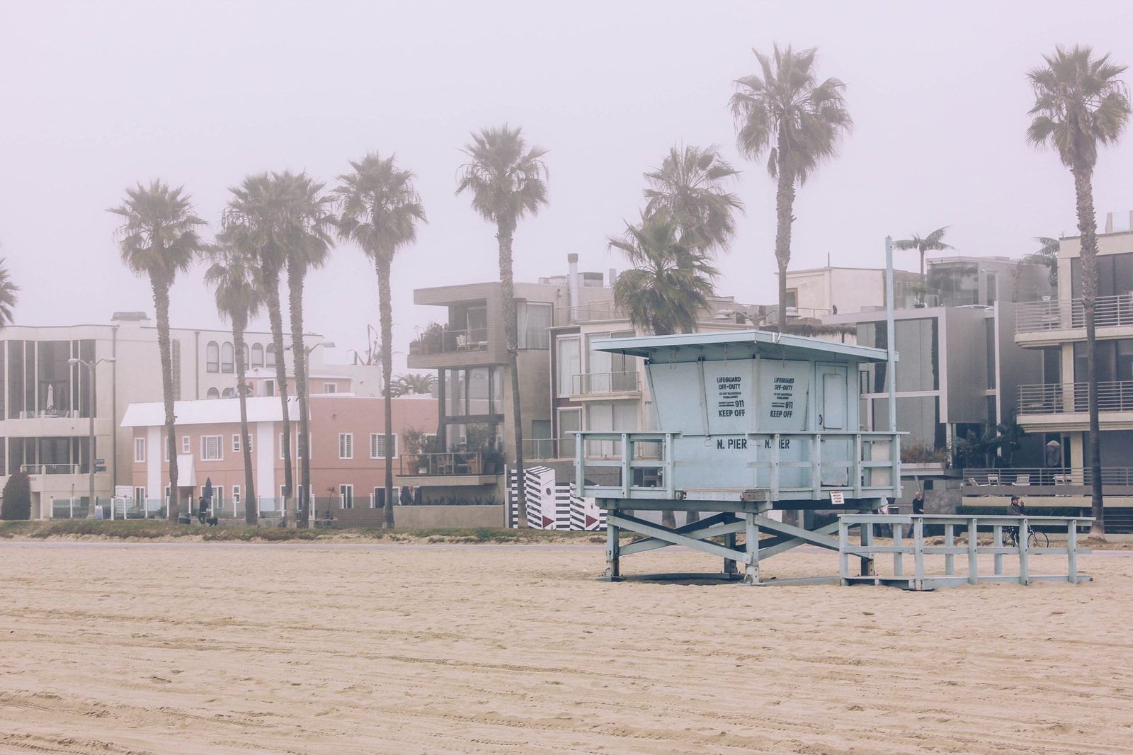 Foggy Los Angeles beach with N. Pier lifeguard tower, palm trees, and coastal buildings