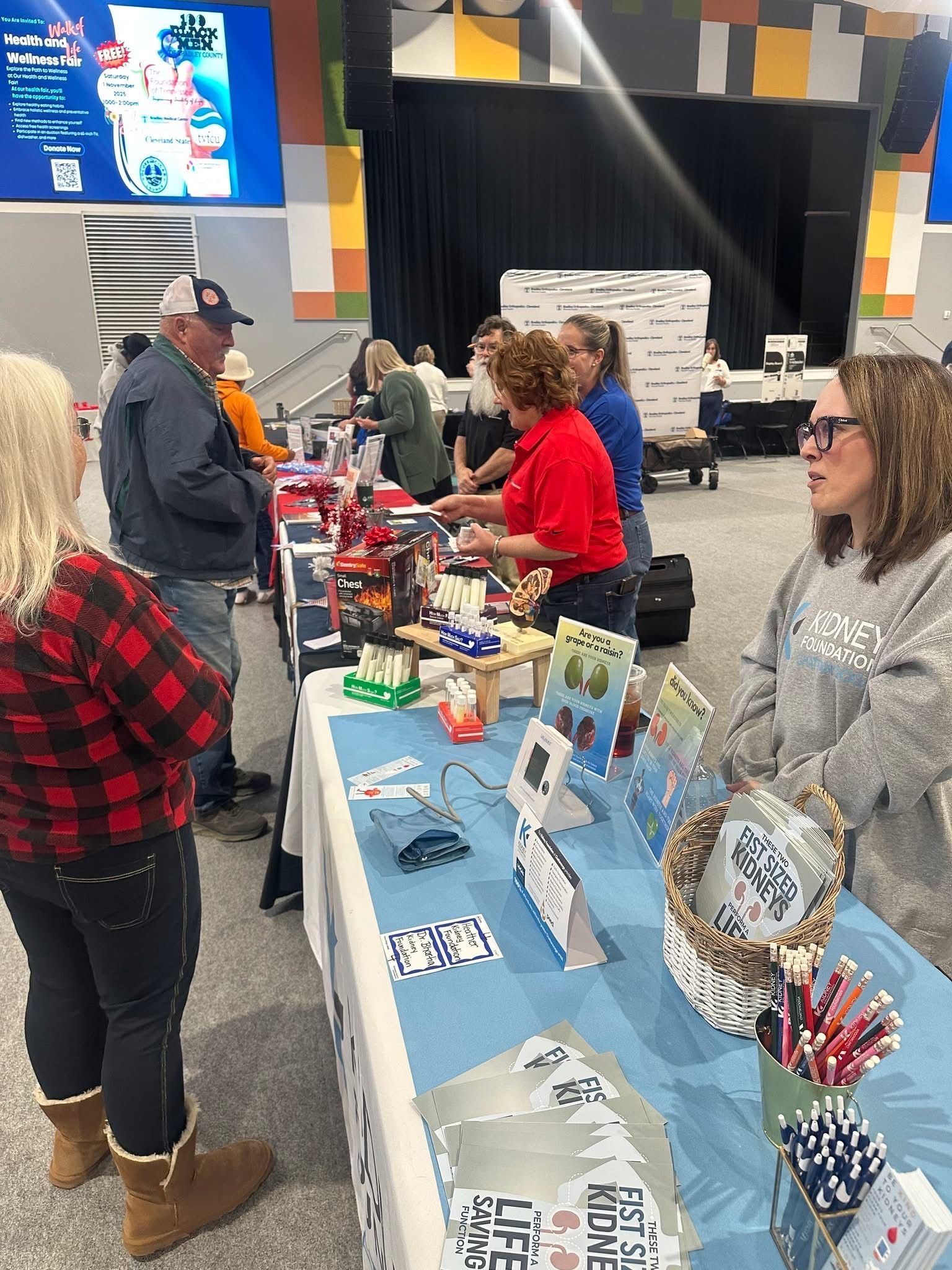 People browsing a vendor table with holiday crafts and gift items in a decorated indoor market