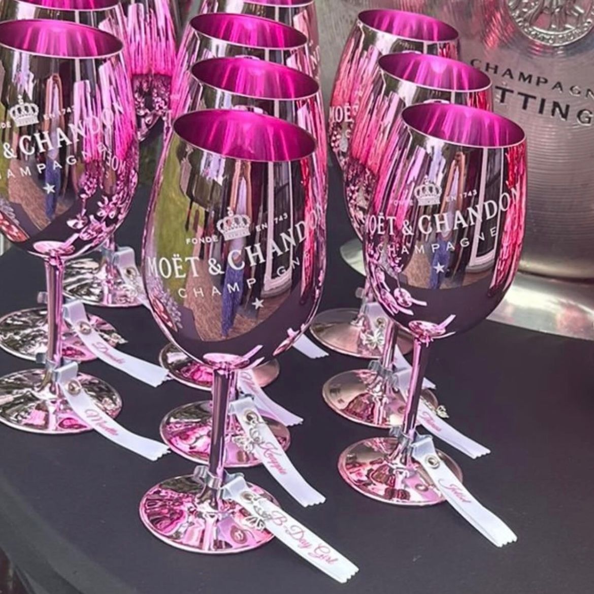  linten met namen met metalen klemmetjes en namen in sierletters. geklemd aan een wijnglas moet Chandon 