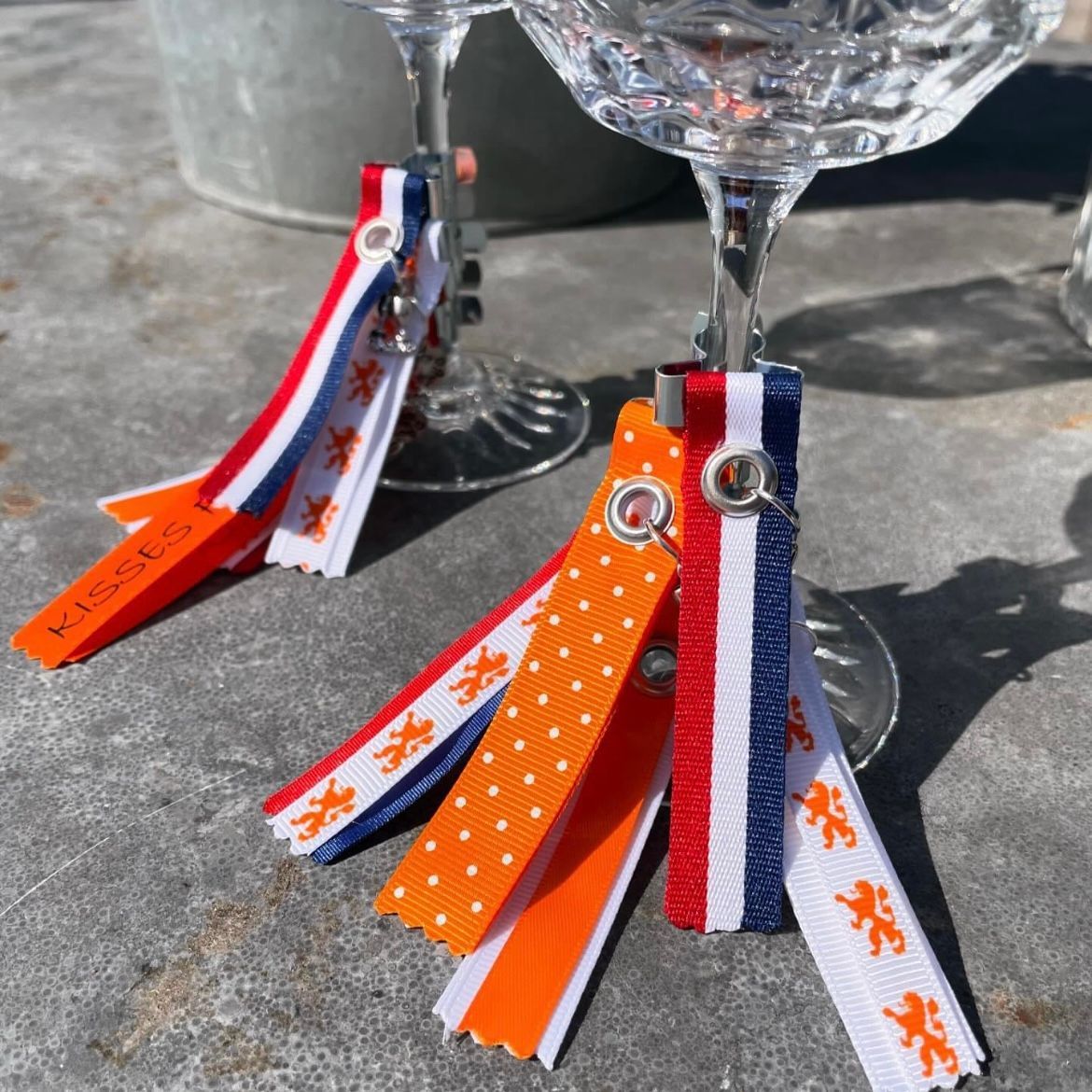 Twee wijnglazen met lintjes in de kleuren van de Nederlandse vlag eraan.