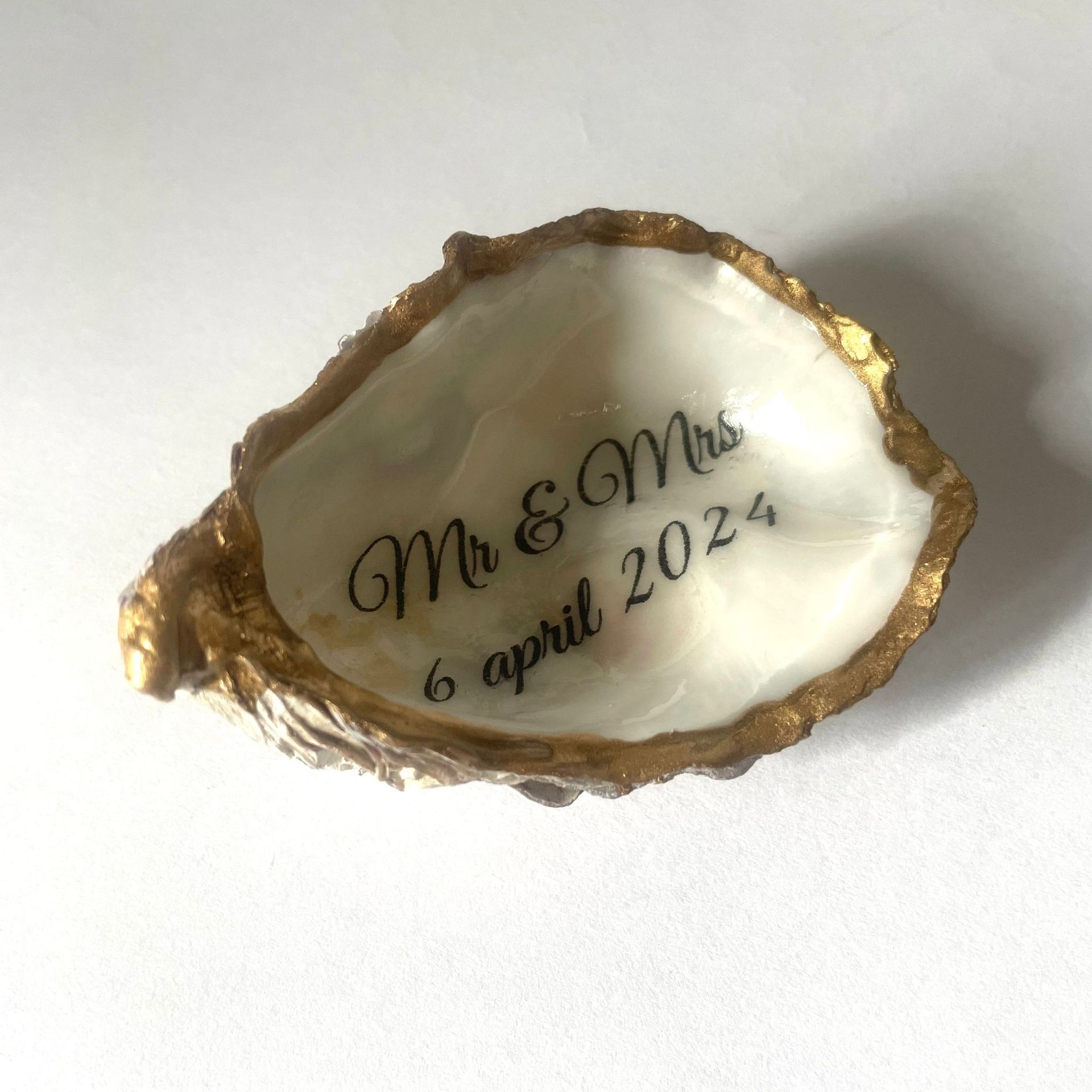 Oesterschelp met gouden rand en gegraveerde tekst: MEP, datum 24 mei 2024.