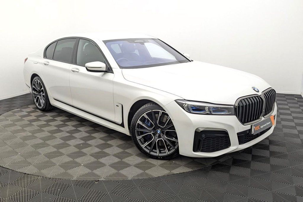 White BMW sedan in a showroom, angled front-left on a patterned floor.