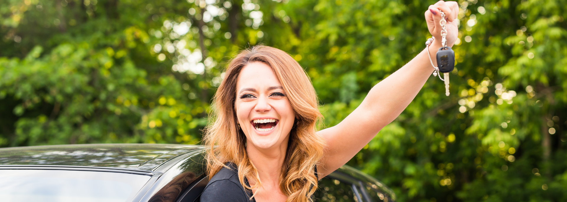 Picture of a woman looking happy leaning out her car holding car keys. Picture of a woman looking happy leaning out her car holding car keys.