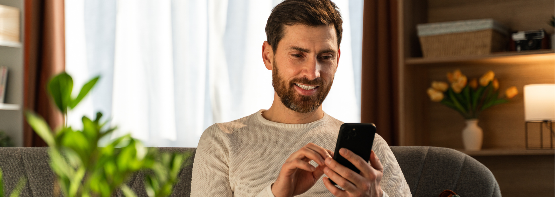 Picture of a man smiling at his phone. 