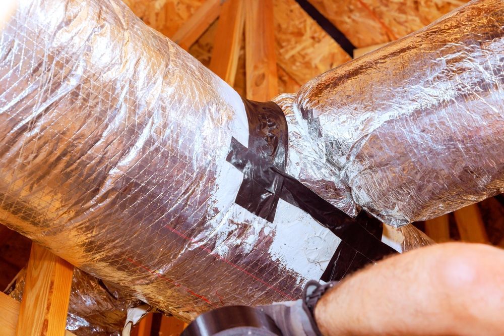 Insulated HVAC ducts joined with black tape in an attic framing space