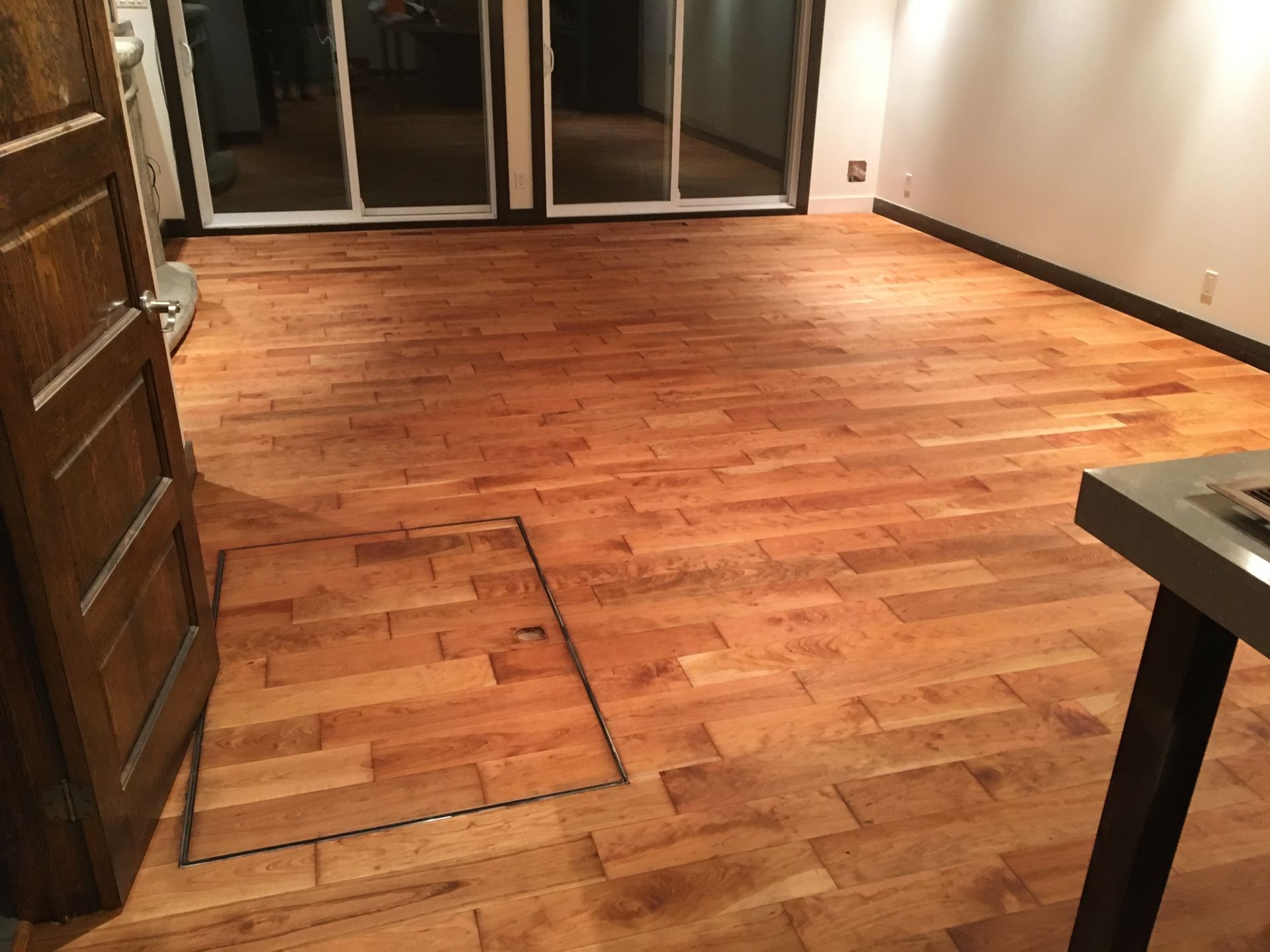 Une pièce avec du parquet et une porte coulissante en verre.