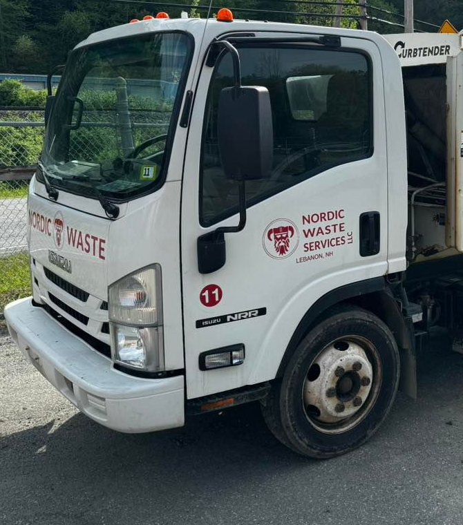 White Nordic Waste Services garbage truck on a road with logo.