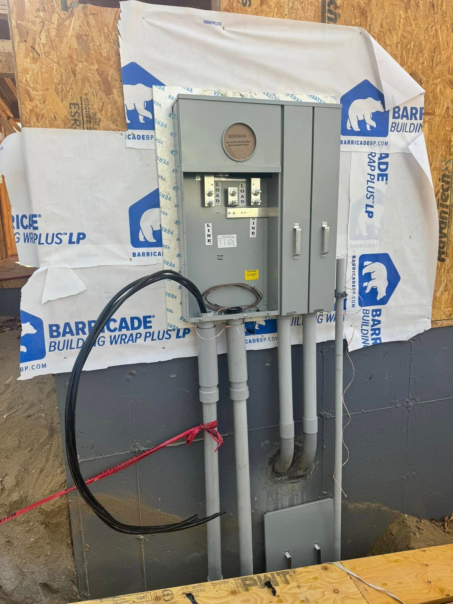 Open electrical meter and conduit on a wall with insulation wrap behind it