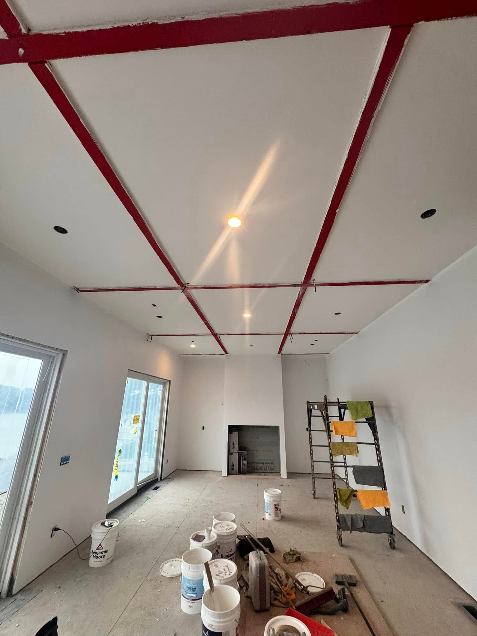 Interior room under renovation with red-taped ceiling, tools, paint buckets, and ladder on the floor