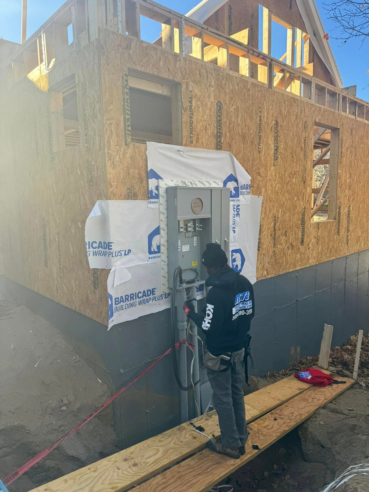 Worker installing exterior wall wrap on a house under construction