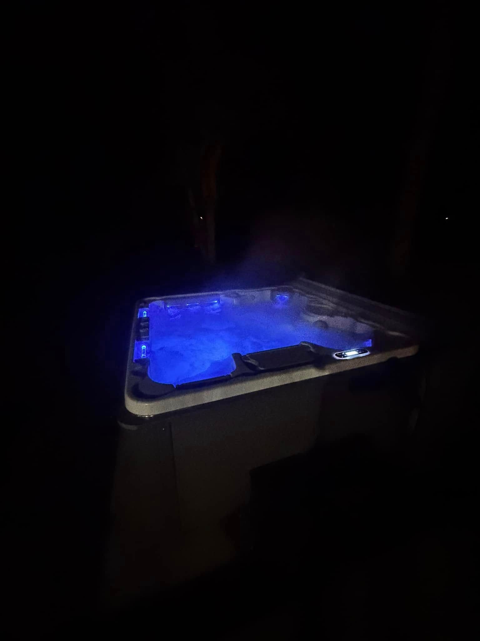 Blue-lit hot tub bubbling in the dark at night