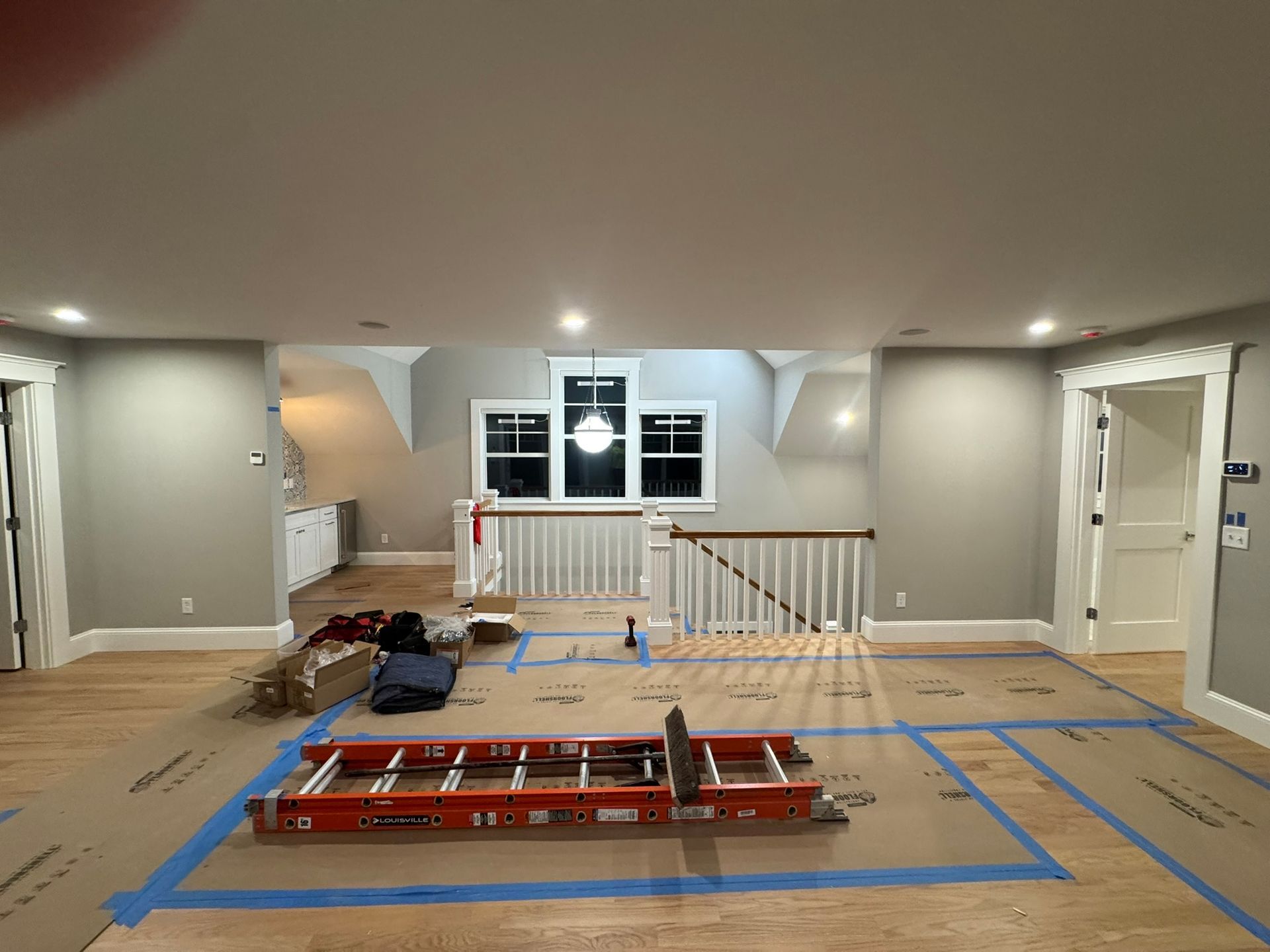 Renovation site in a finished room with blue tape layout lines and red equipment on the floor